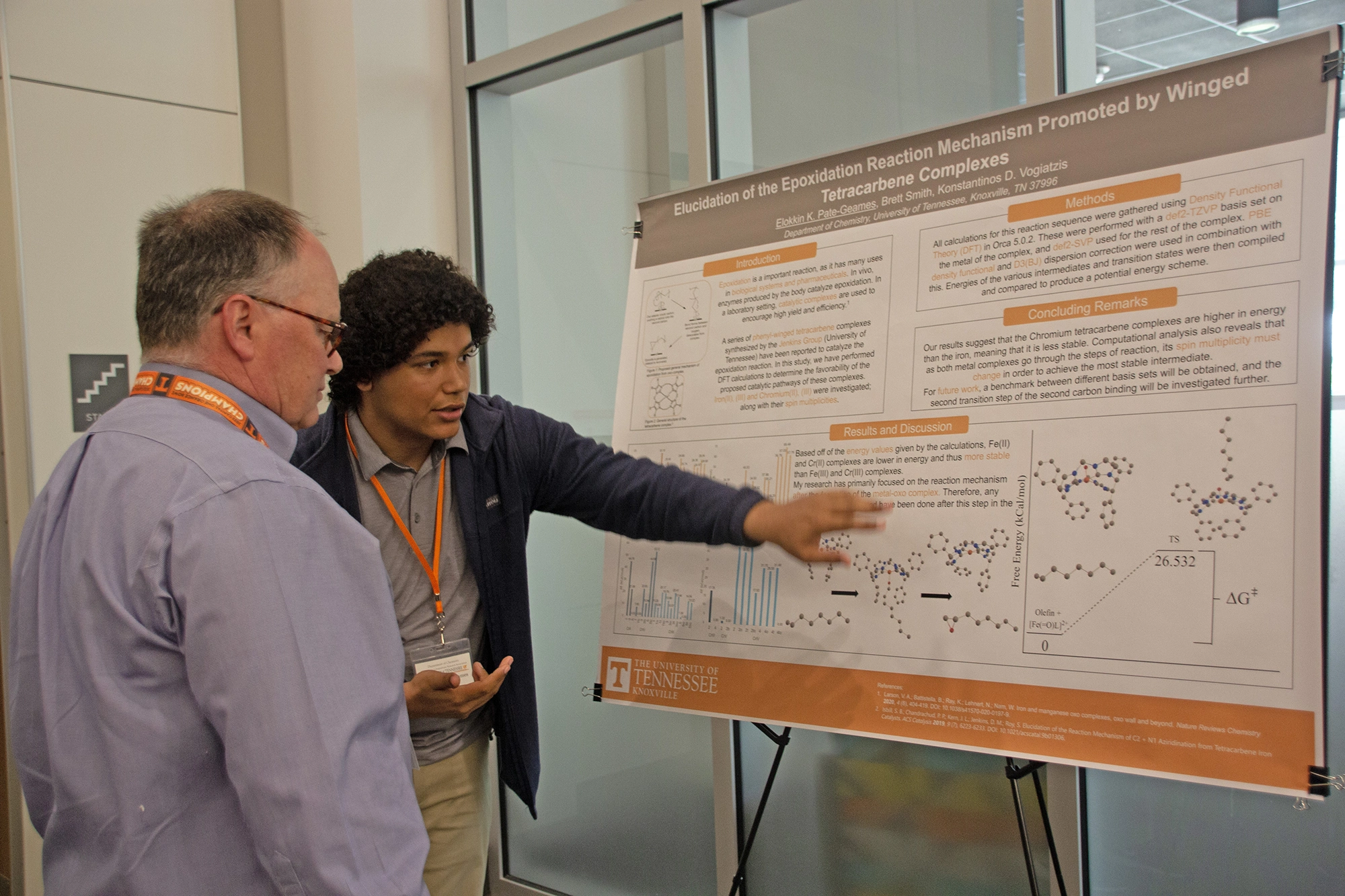 A student talking with a professor points at a research poster