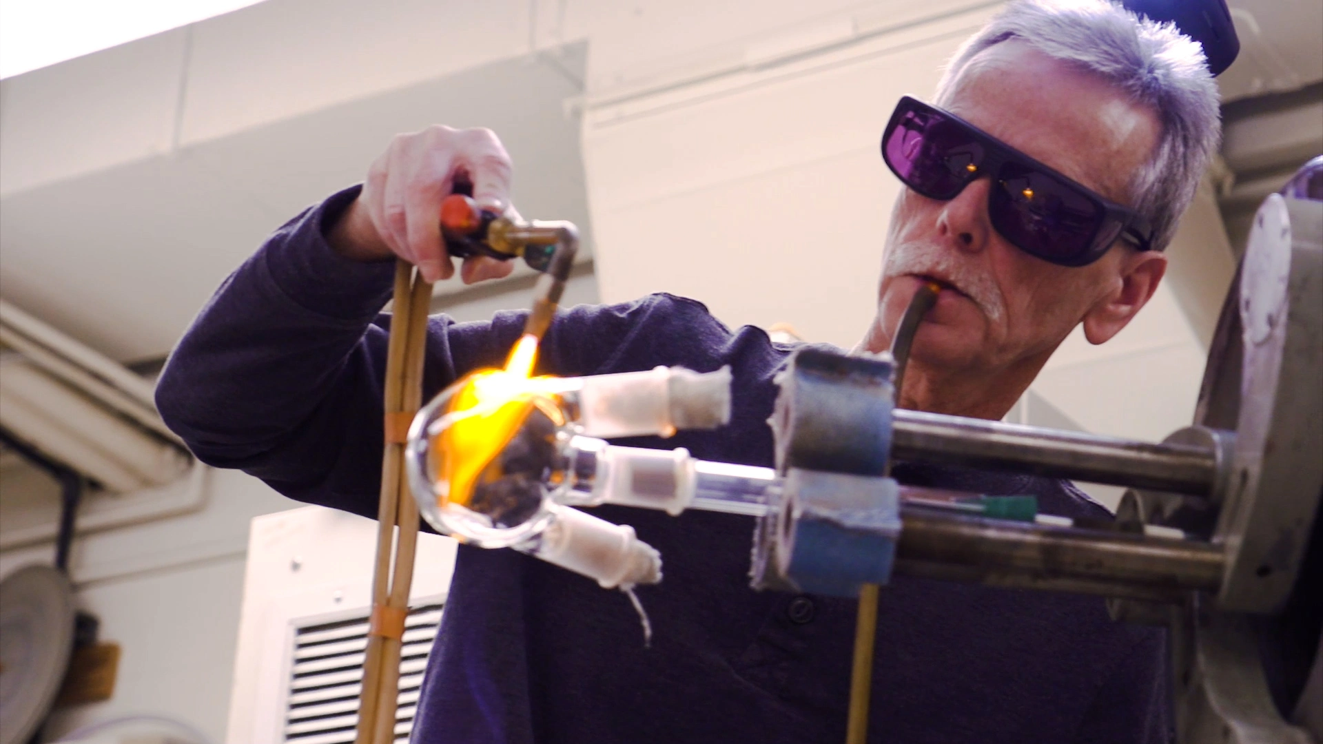 A man with safety glasses fabricating glass