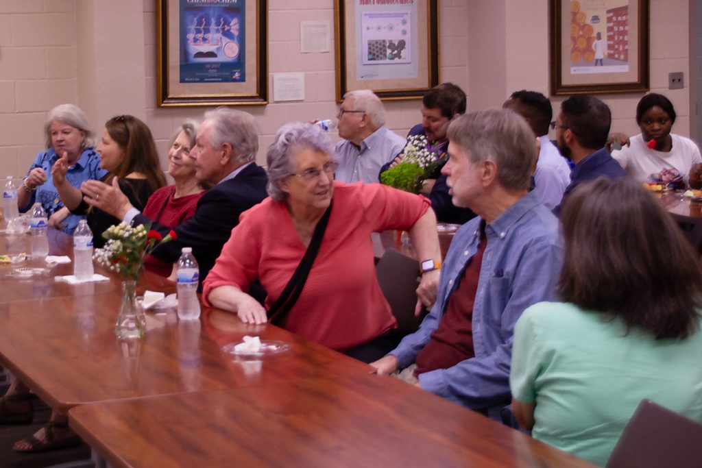 Guests at Honors Day sit at long tables talking with one another.
